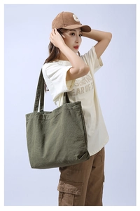 Side view of model wearing a large olive green canvas tote bag with durable straps