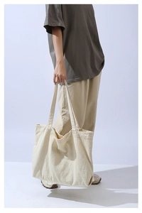 Detail of wide shoulder straps on a beige minimalist large canvas tote bag