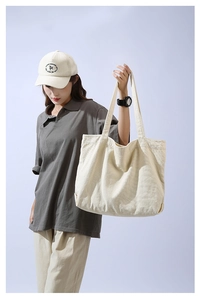Detail of a large beige canvas tote bag showing the high-density fabric and double handles