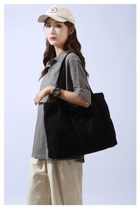 Side view of large black canvas tote bag on female model for daily commuting use