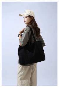 Macro detail of large black canvas tote bag showing material texture and shoulder strap fit