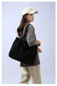 Minimalist large black canvas tote bag shown on shoulder for size and drape reference