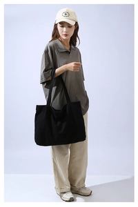 Minimalist black canvas tote bag styled with casual outfit in a professional studio setting