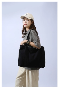 Side view of large black canvas tote bag on model showing size and natural drape