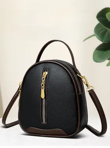 Detail of black pebbled leather bucket bag with brown trim and gold-tone zippers