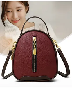 Detail of burgundy lychee leather bucket bag with gold zipper and chain pendant