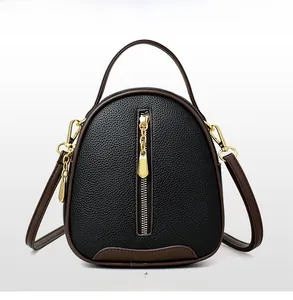 Detail of black pebbled leather bucket bag with brown trim and gold vertical zipper