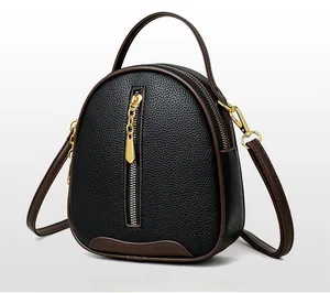 Detail of black pebbled leather bucket bag with brown trim and vertical gold zipper accent