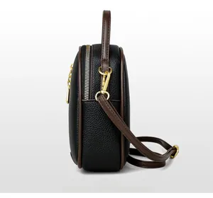 Side view detail of black lychee leather bucket bag with brown trim and gold hardware