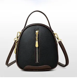 Close-up of litchi-grain leather bucket bag with brown handles and gold hardware accents