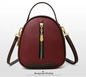 Close-up of wine red bucket bag with litchi grain texture and gold-tone metal hardware