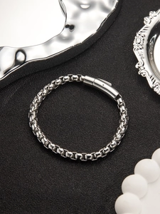 Primo piano di un bracciale a catena da uomo in acciaio inossidabile lucido su sfondo nero
