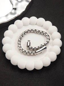 Dettaglio del bracciale a catena box in acciaio argento con chiusura a cilindro su vassoio
