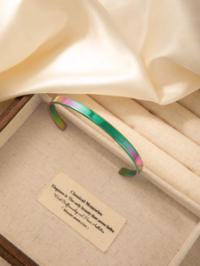 Close-up of a gradient rainbow metallic cuff bracelet in a luxury jewelry box
