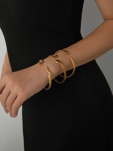 Detailed close-up of 18k gold plated snake-shaped cuff bracelets with scale texture