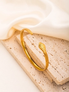 Detailed close-up of golden snake-shaped cuff bracelet with intricate scale textures