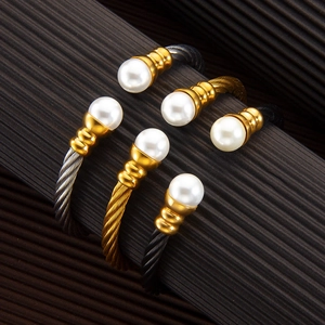 Detailed view of three twisted cable bracelets with pearl accents in gold and silver