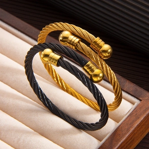 Macro detail of two-tone twisted cable bracelets in gold and black on a velvet tray