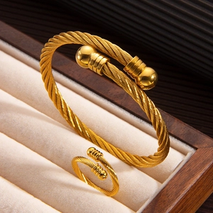 Detail of gold twisted cable cuff bracelet and matching ring set in a luxury jewelry box