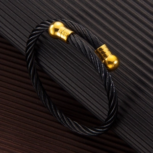 Detail view of twisted black steel cable bracelet with gold-plated ribbed ball ends