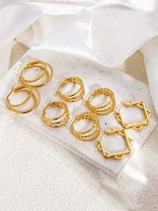Detailed arrangement of 18k gold plated geometric hoop earrings on a stone background