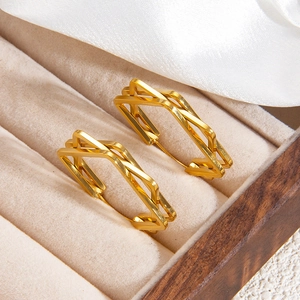 Macro shot of gold geometric triple-line earrings on beige velvet display box