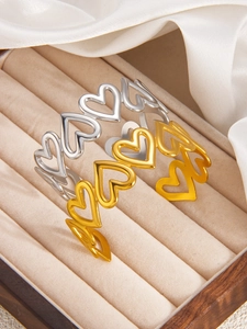 Detail of hollow heart open bangles in gold and silver finish on soft silk fabric