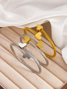 Detail of twisted cable heart bangles in gold and silver finish on velvet display
