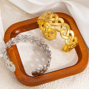 Detail of gold and silver hollow woven open bracelets in a premium wooden display