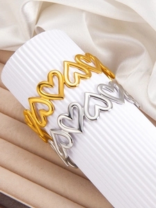 Detailed view of hollow heart patterns on gold and silver stainless steel bangles