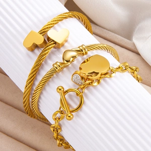 Macro shot of 18k gold plated stainless steel heart bracelet and twisted rope bangle set