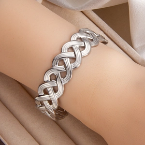 Close-up of a silver hollow woven open cuff bracelet worn on the wrist with elegant jewelry box