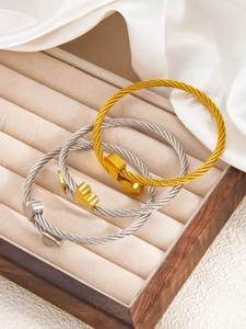 Detailed view of woven metal texture bracelets with polished heart charms in a jewelry box