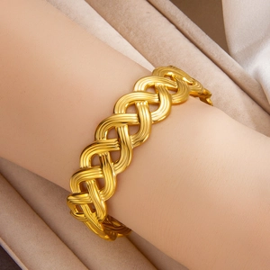 Detail shot of wide hollow 18k gold plated woven bracelet on a soft velvet box