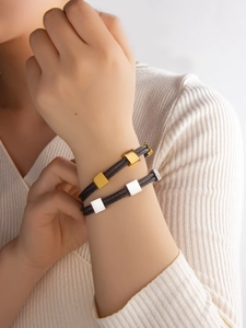Detalle de pulseras de cable negro ajustables con controles de oro de 18k y plata