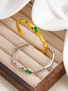 Detail view of irregular hammered 18k gold and silver bangles with emerald zircon gems