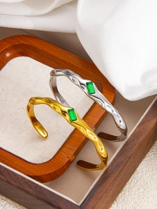 Detail of 18k gold and silver irregular hammered bracelets with green emerald stones
