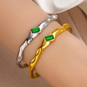 Wavy 18k gold and silver plated emerald bangles featuring a rectangular green gemstone