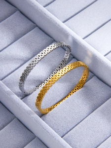 Close-up of gold and silver hollow grid mesh bangles in a jewelry organizer tray