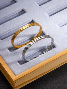 Detailed macro view of gold and silver mesh weave bracelets in a velvet display case