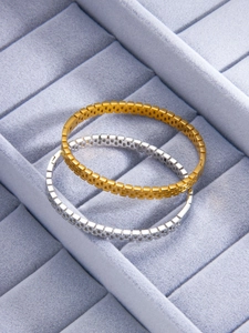 Detail of hollow grid titanium steel bracelets in gold and silver finish on velvet