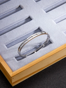 Macro shot of silver hollow double-rail bangle with inlaid zircons on jewelry display