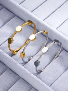 Detailed macro view of three twisted cable bangles in gold, silver, and two-tone finishes