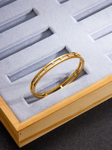 Detailed view of hollow gold-plated bangle with sparkling inlaid cubic zirconia stones