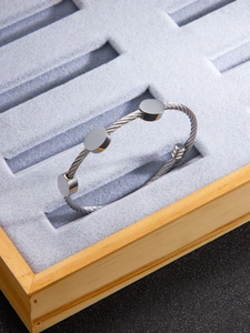 Detail of twisted cable stainless steel bangle with circular metal plates on velvet