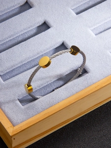 Detailed view of twisted steel wire bracelet with three 18k gold-plated circular accents