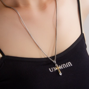 Collana hip hop con ciondolo a doppia croce bicolore argento e oro indossata da un uomo