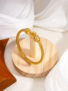 Detailed shot of gold-plated twisted cable bracelet with pavé horseshoe clasp buckle