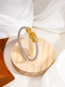 Macro detail of two-tone twisted cable bracelet with pavé diamonds on horseshoe clasp