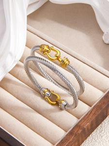 Macro shot of twisted silver rope bracelet with gold diamond horseshoe clasp on velvet